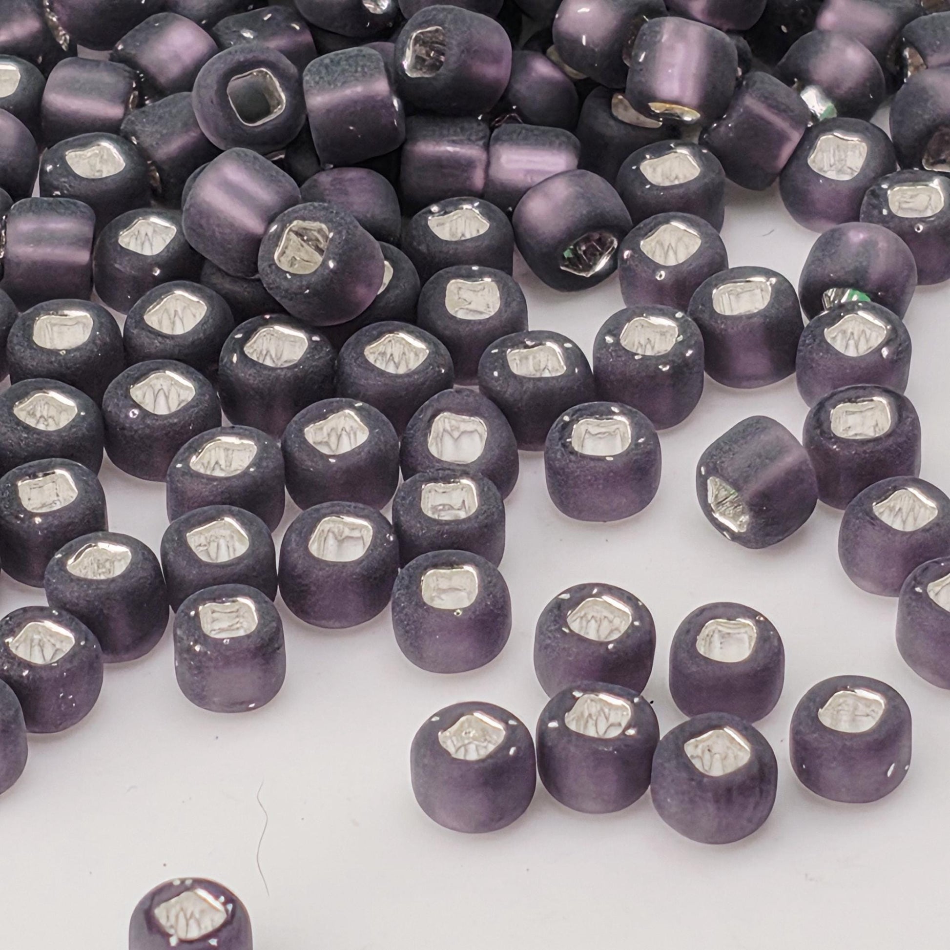 a collection of purple glass beads scattered across a white background.