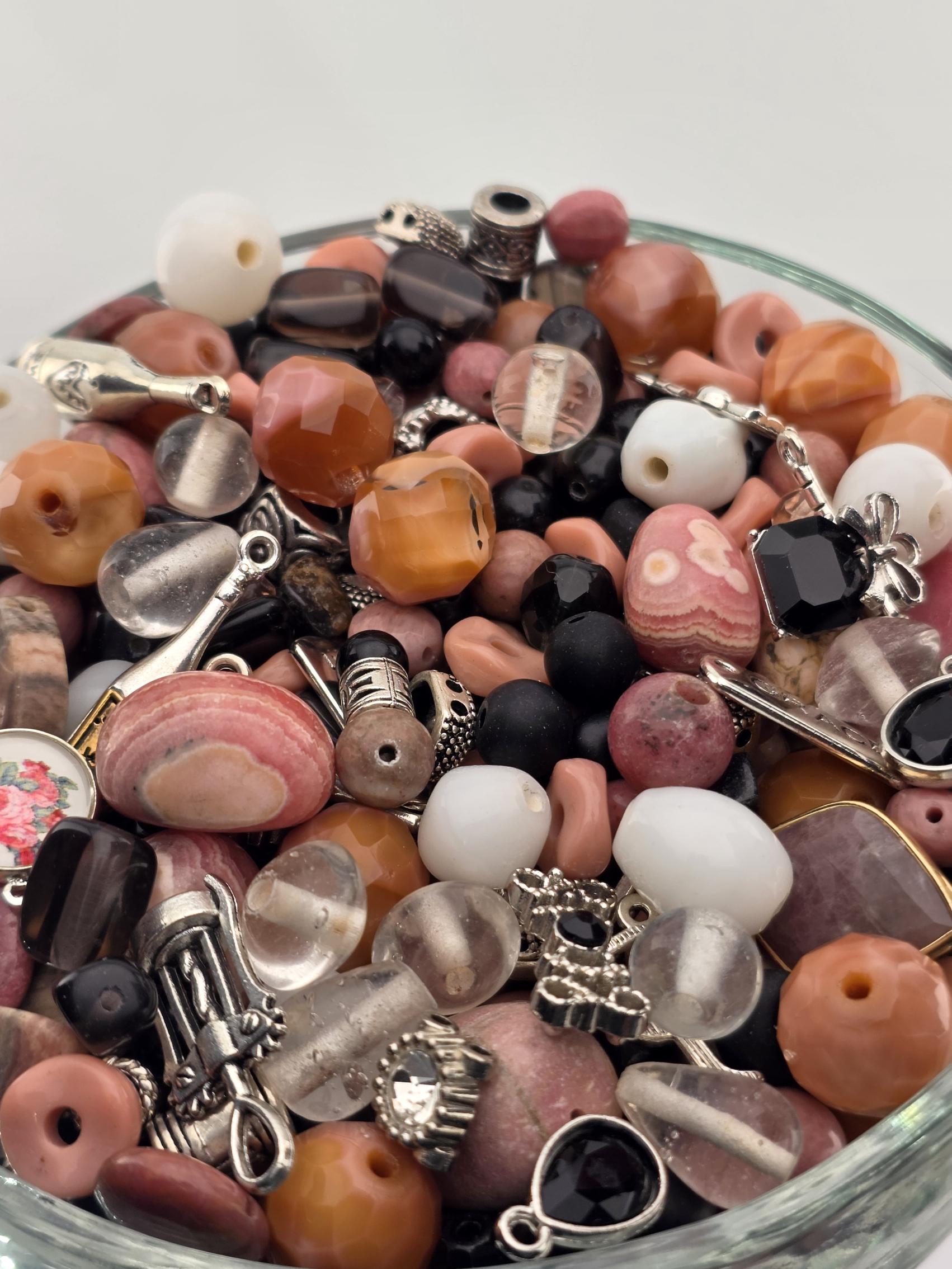 A glass bowl filled with various beads, charms, and other small decorative items.