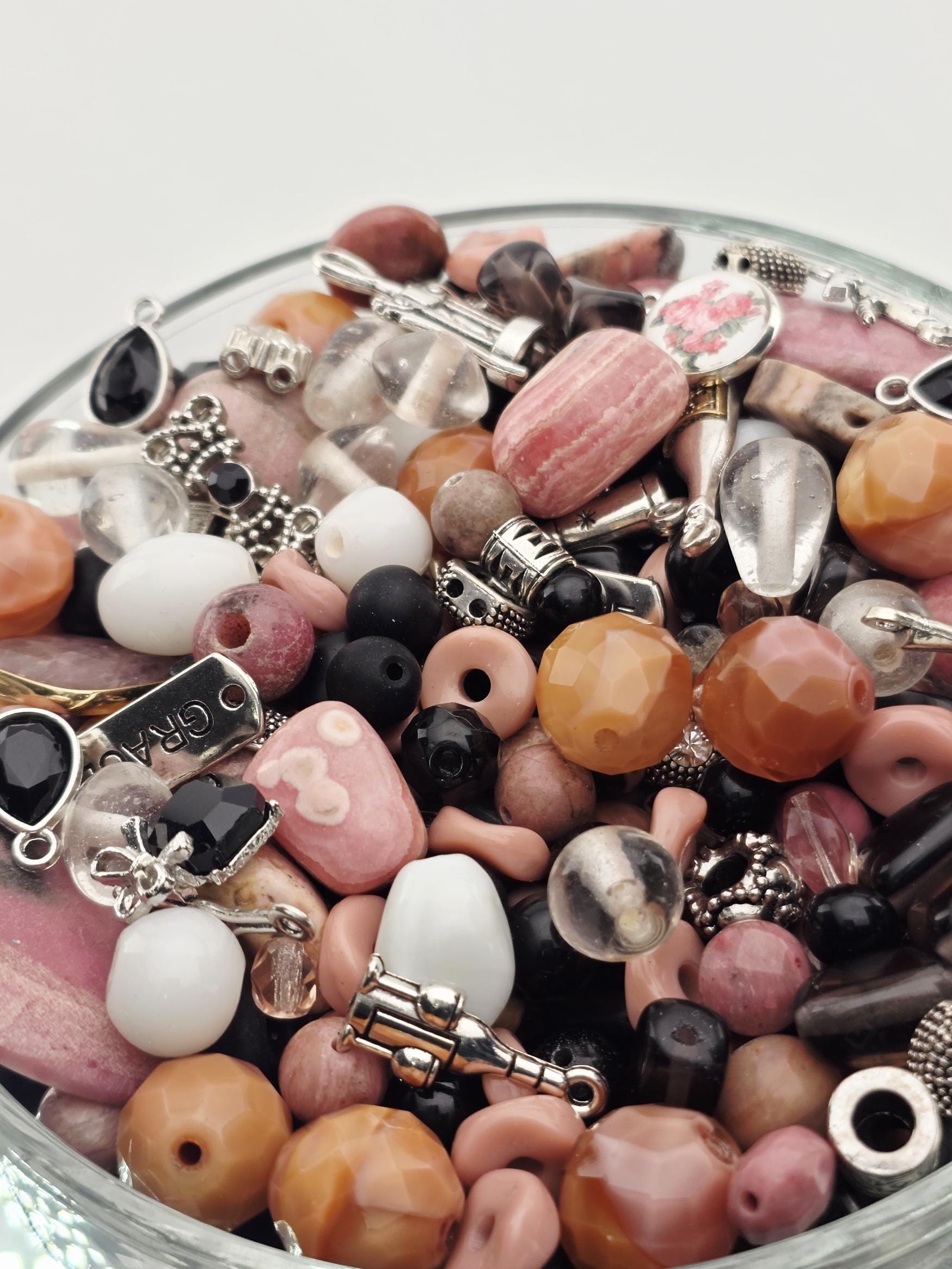 A glass bowl filled with various beads, charms, and other decorative items.