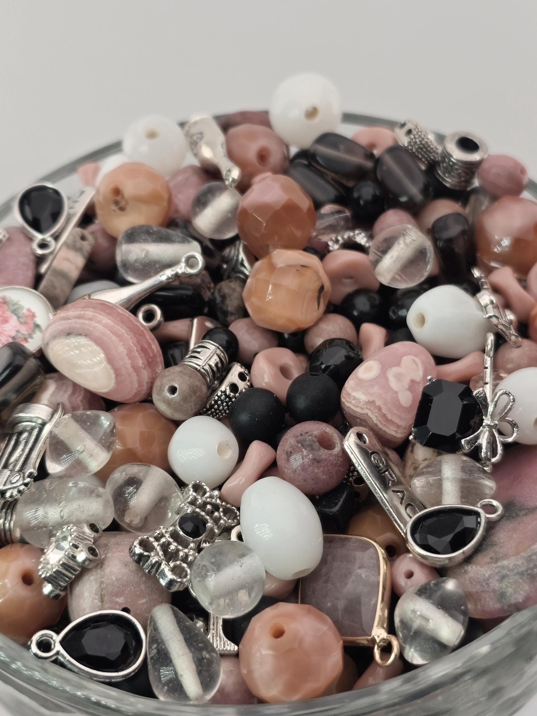 A bowl filled with various beads, charms, and other decorative items.