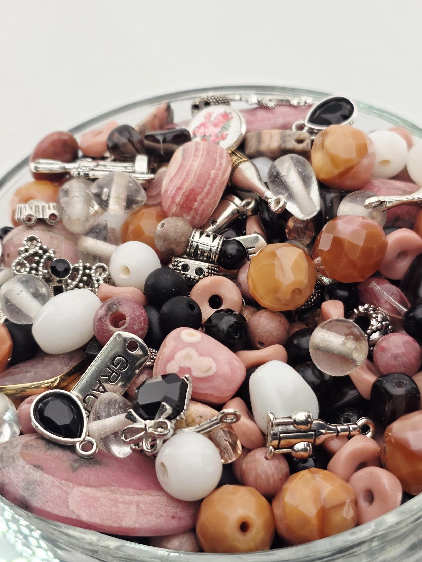 A glass bowl filled with various beads, charms, and other decorative items.