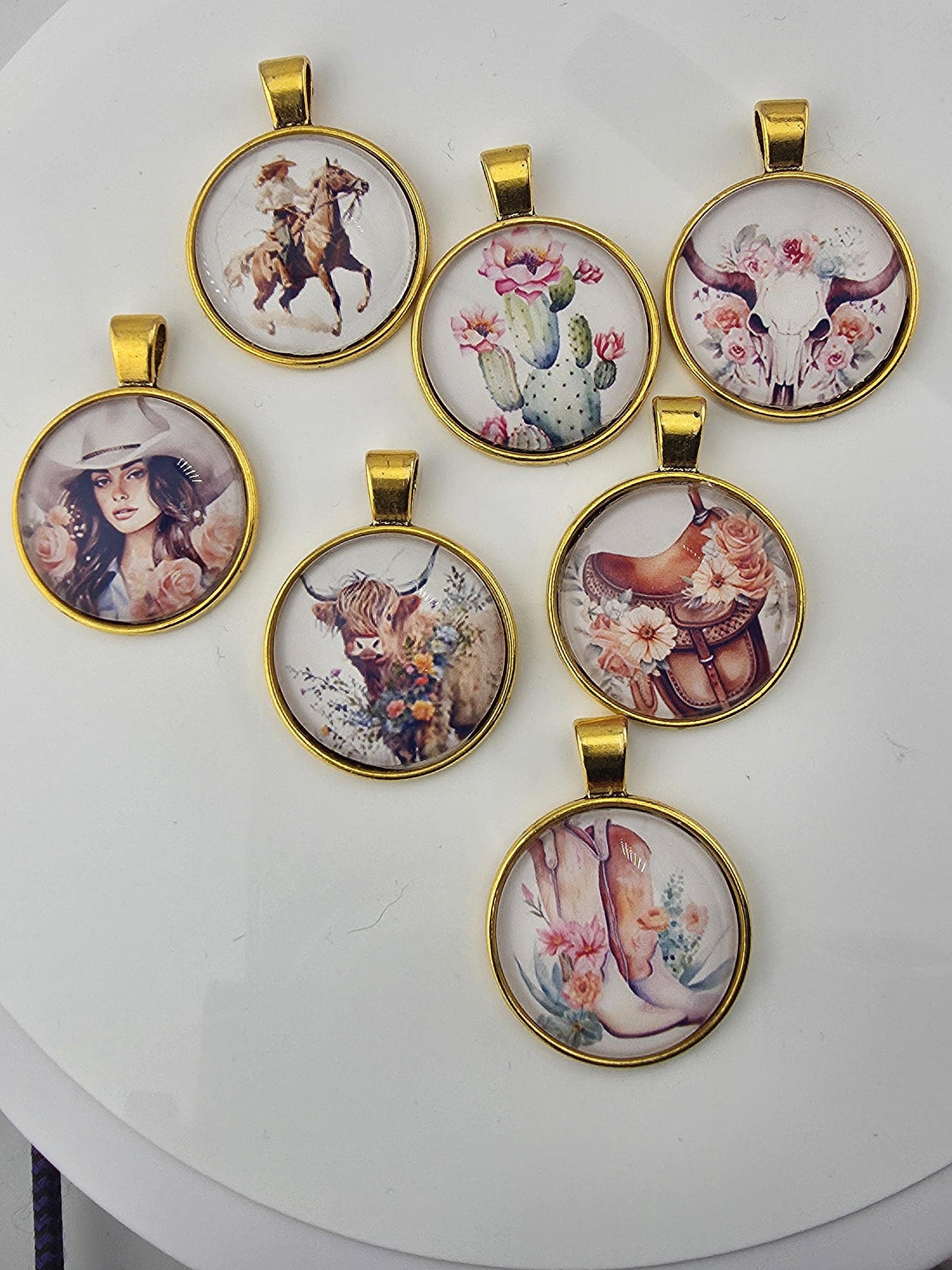 a collection of seven round pendants with various floral and animal designs, all attached to a white surface.