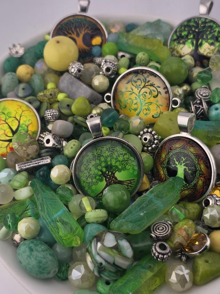 The image is a collection of various colorful beads, charms, and pendants, including green, yellow, and silver elements, arranged on a surface.