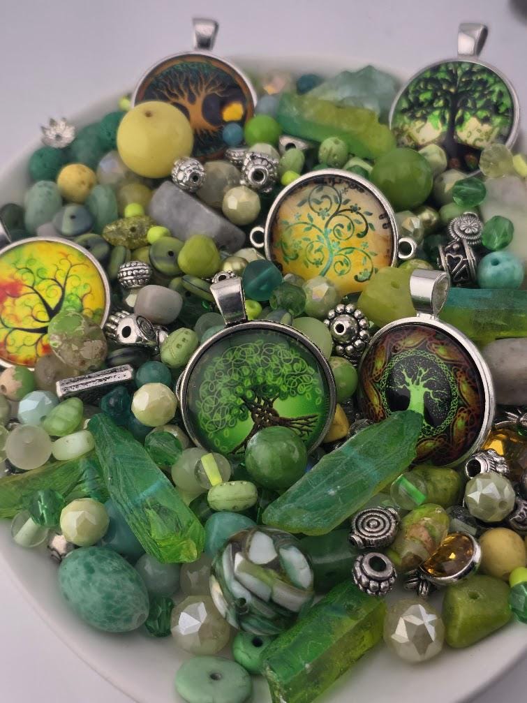 a collection of various green and yellow beads, charms, and pendants arranged on a white surface.