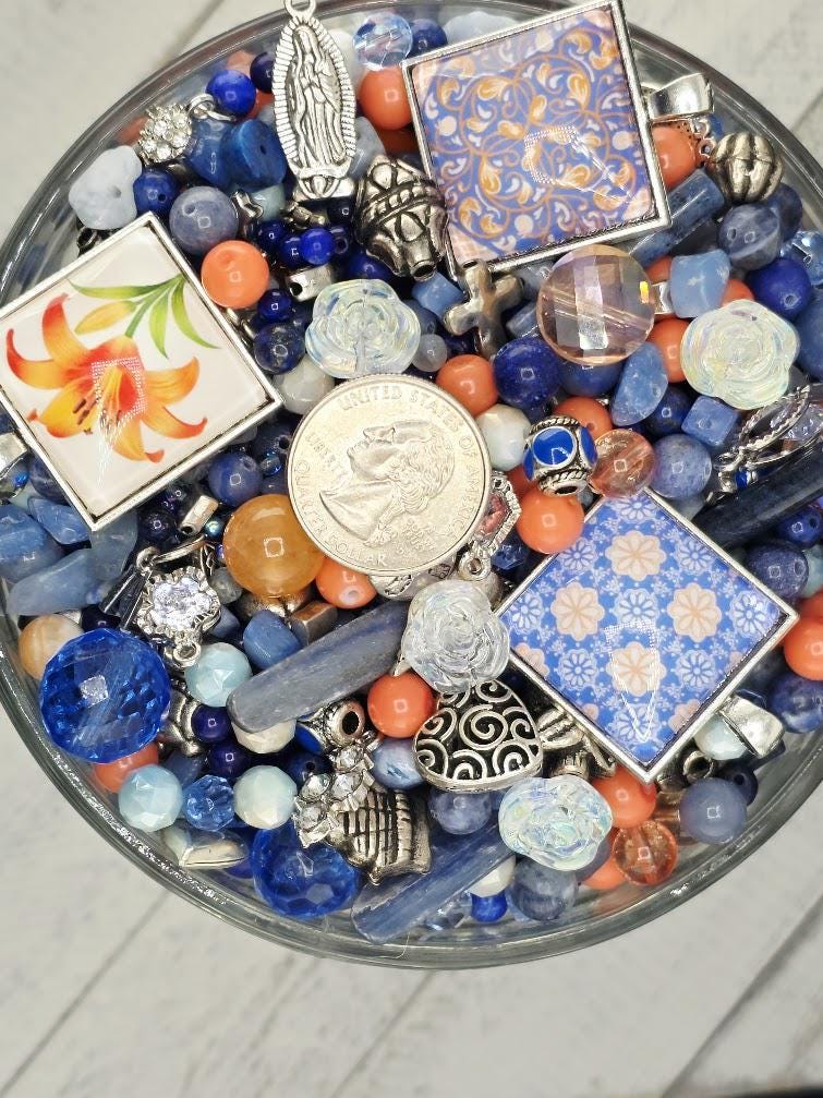 A glass bowl filled with various colorful beads, charms, and other small decorative items.