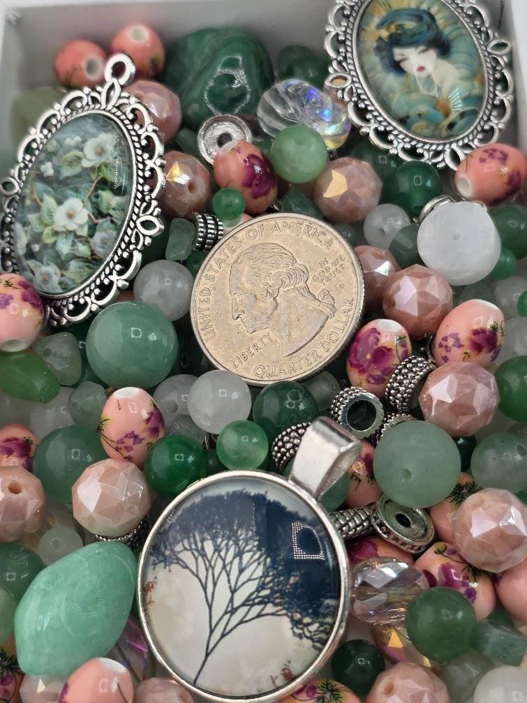 various beads, charms, and a coin, creating a visually appealing and diverse collection of jewelry-making materials.