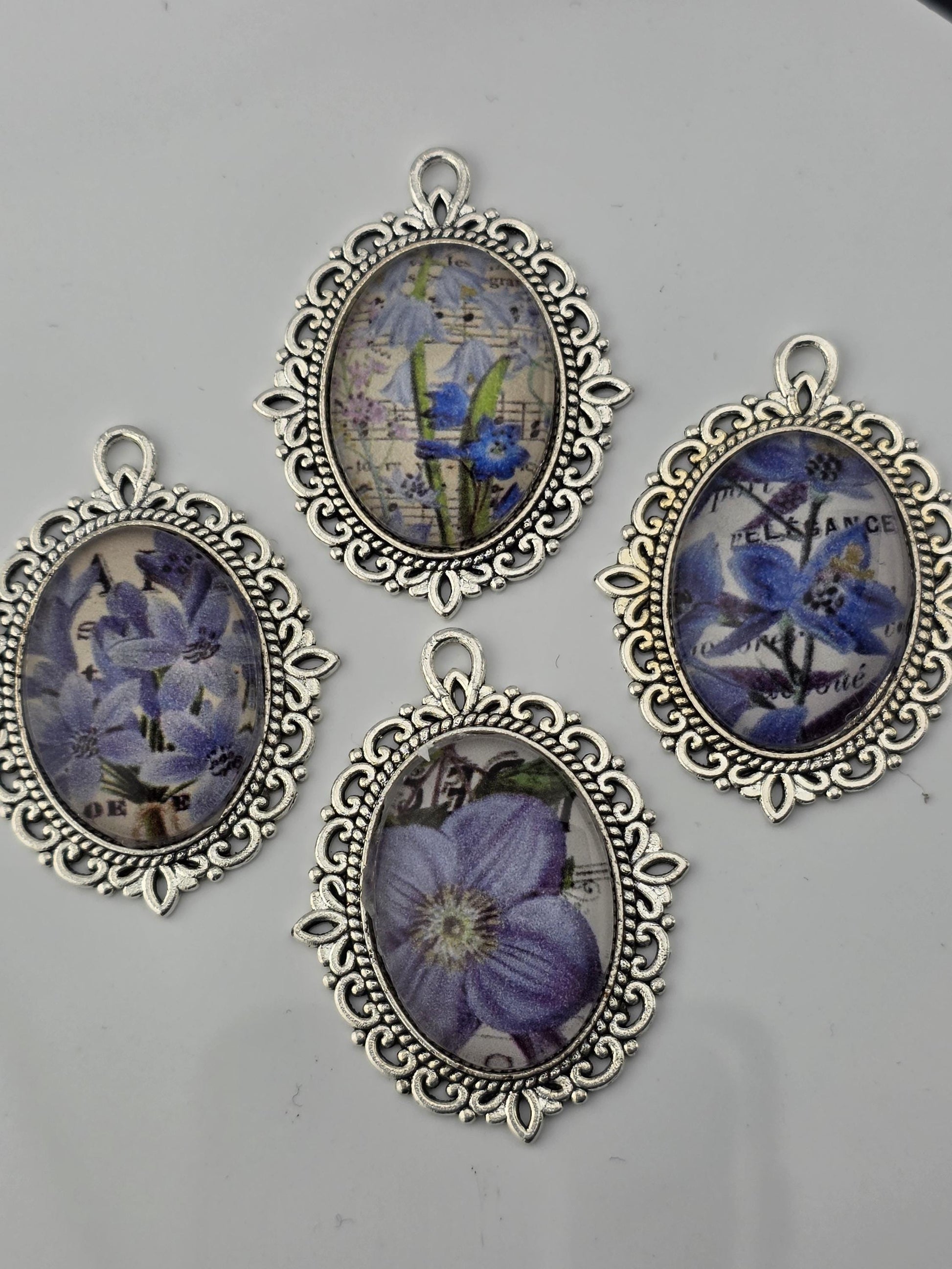four oval-shaped pendants with floral designs, each framed in an ornate, decorative metal frame.