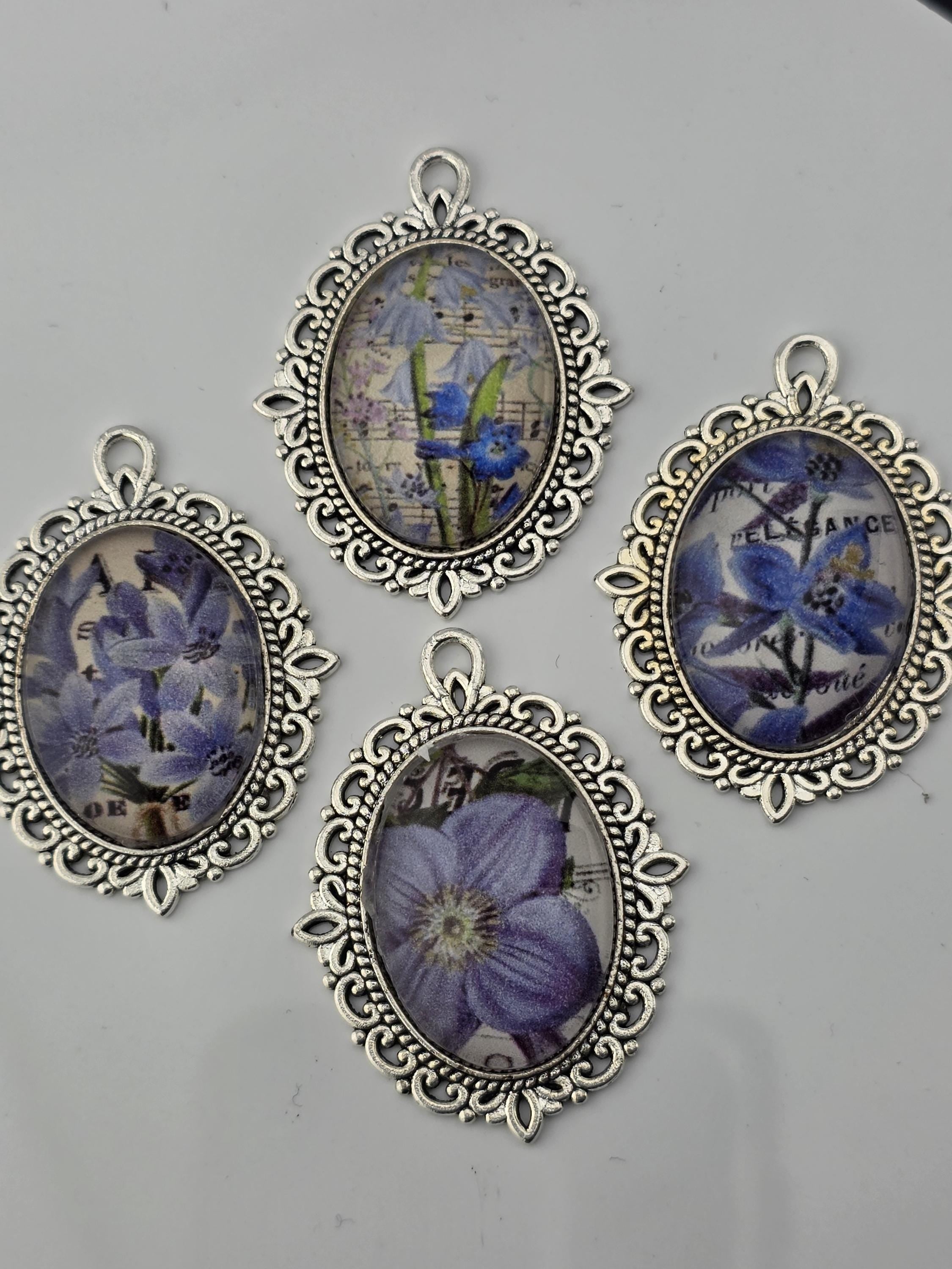 four oval-shaped pendants with floral designs, each framed in an ornate, decorative metal frame.