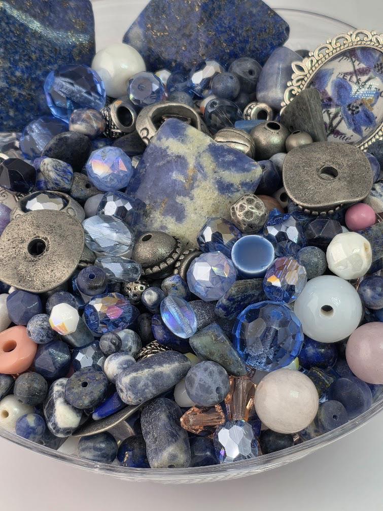 a variety of colorful beads and jewelry pieces, including blue, silver, and pink beads, as well as some metal components.