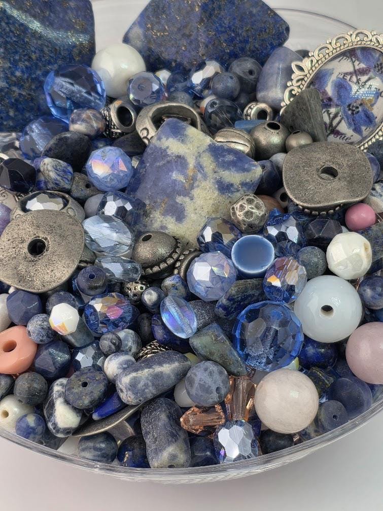 a variety of colorful beads and jewelry pieces, including blue, silver, and pink beads, as well as some metal components.