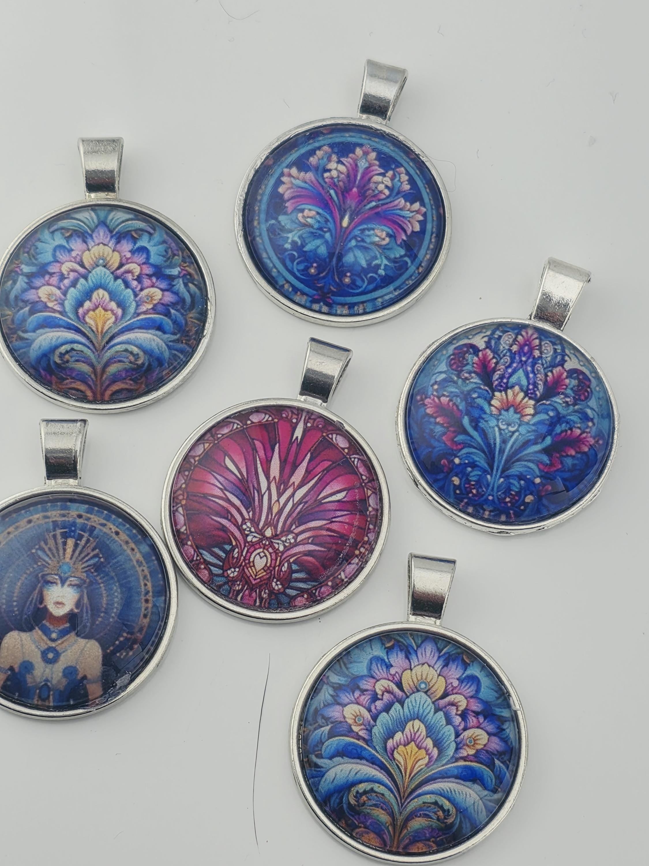 six colorful pendants with intricate designs, including floral patterns and abstract shapes, arranged on a white background.