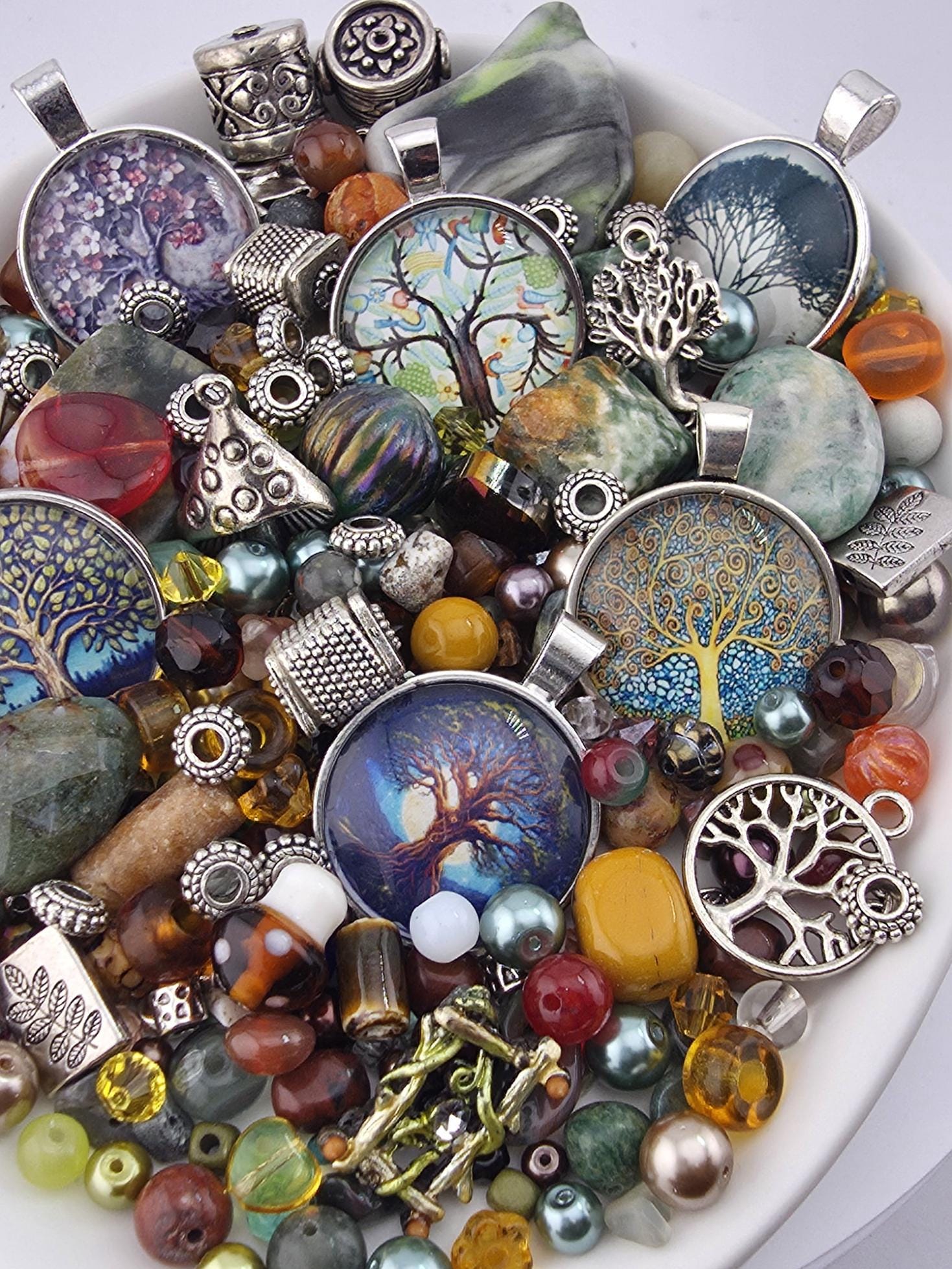 A bowl filled with various colorful beads, charms, and pendants, including glass beads, metal charms, and other decorative elements.