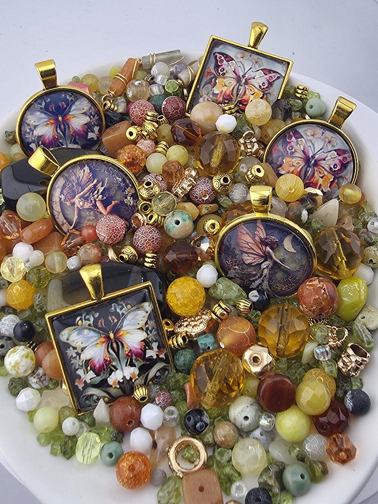 The image is a collection of various colorful beads, charms, and pendants, including butterfly-themed designs, arranged on a white surface.