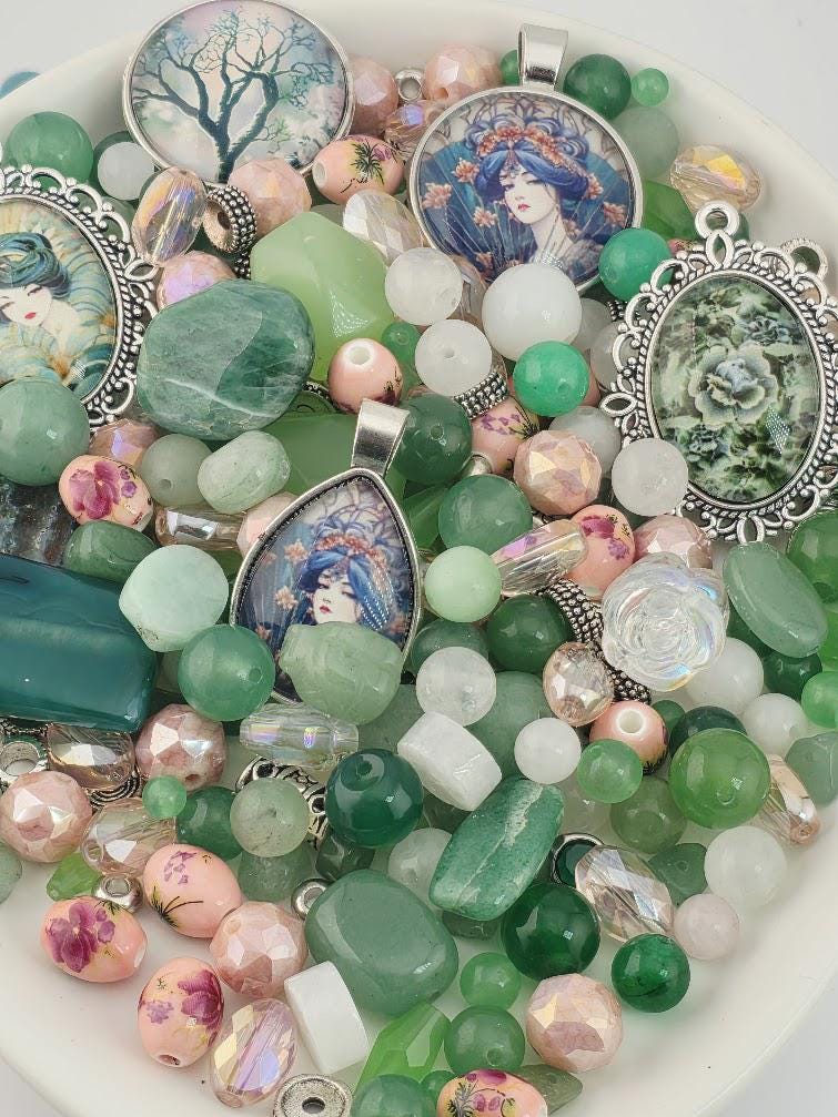 The image is a collection of various beads, charms, and pendants, including glass beads, gemstones, and metal pendants, all arranged on a white surface.