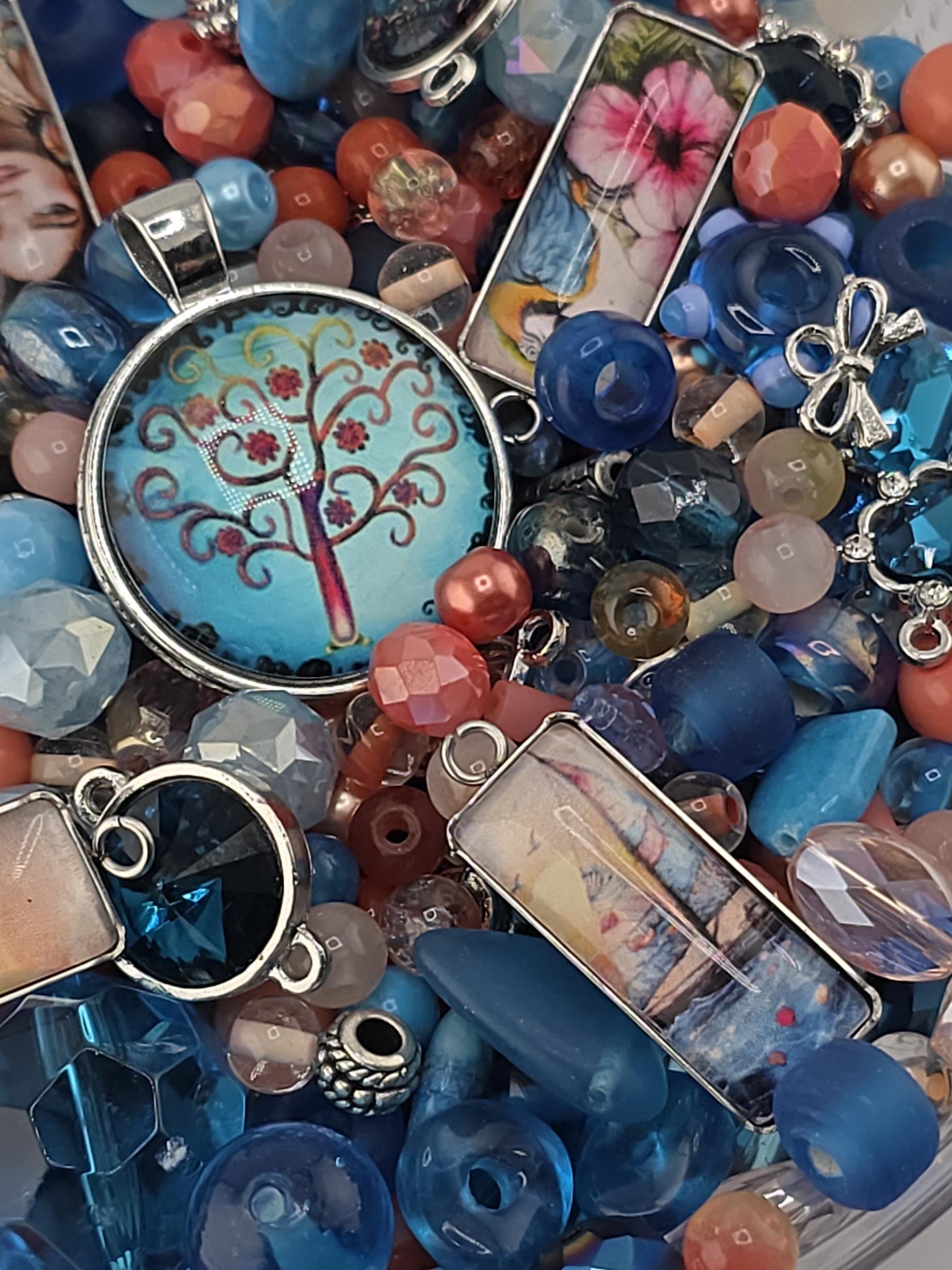 The image is a colorful assortment of various beads, charms, and pendants, including blue, pink, and silver elements, creating a visually appealing and diverse collection.
