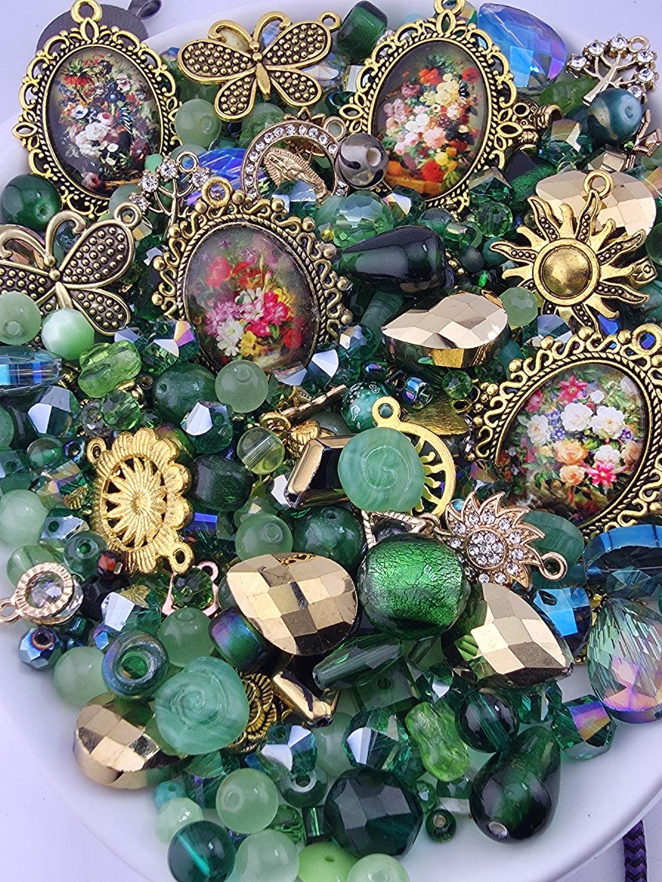 The image is a collection of various colorful beads, charms, and trinkets, including green, gold, and floral designs, arranged on a surface.