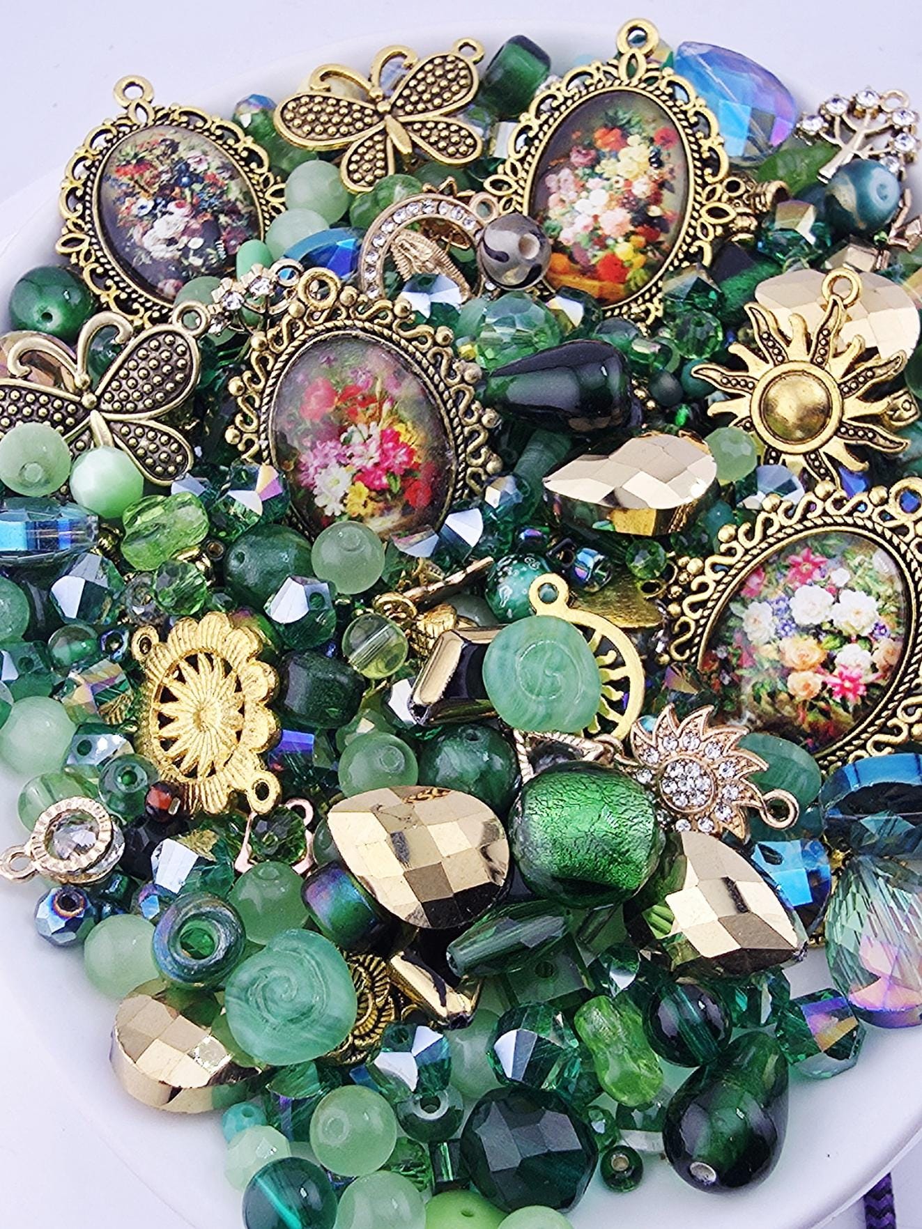 The image is a collection of various colorful beads, charms, and trinkets, including glass beads, metal charms, and other decorative elements, all arranged on a white surface.