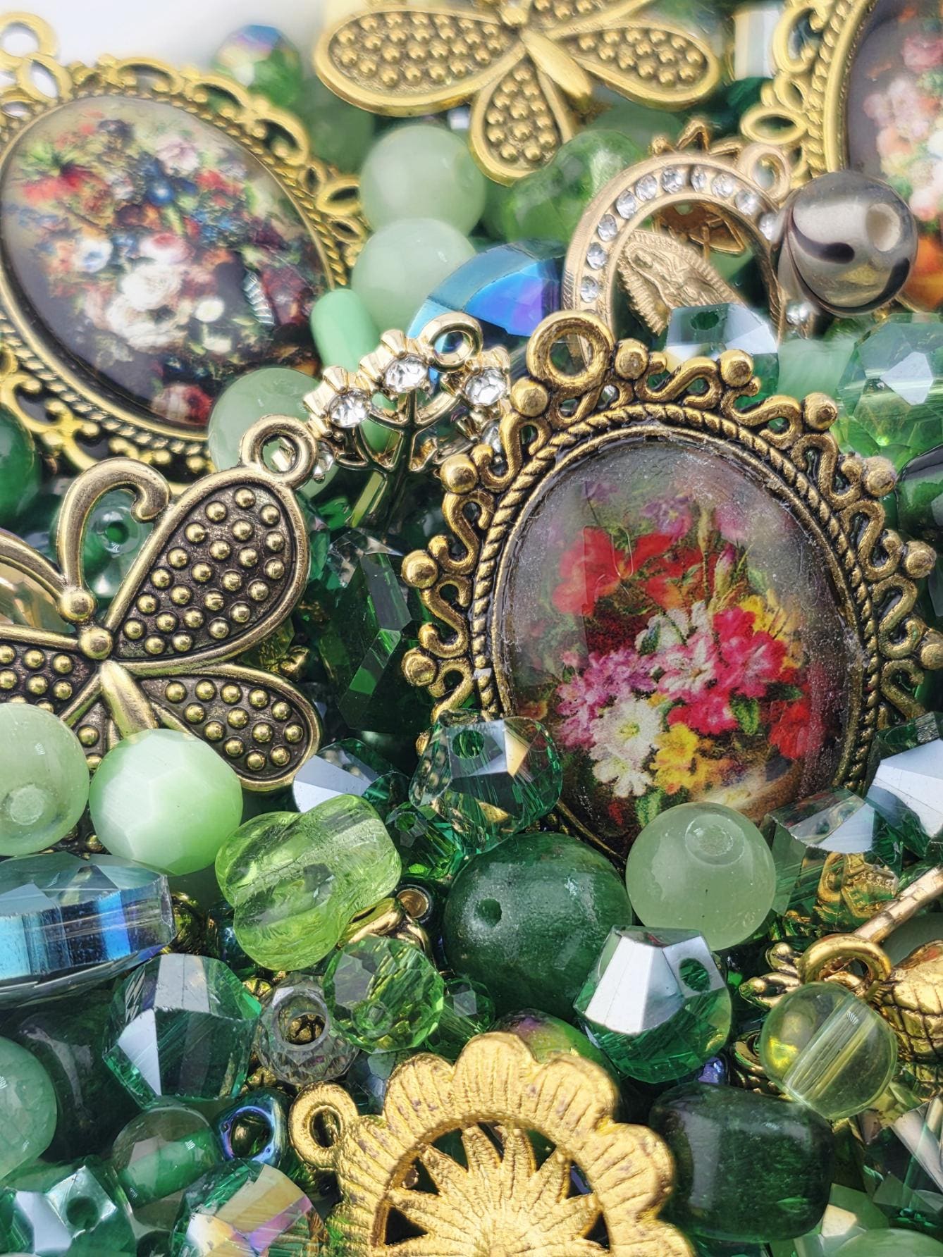 The image is a close-up of a collection of various colorful beads, charms, and trinkets, including a pendant with a floral design.