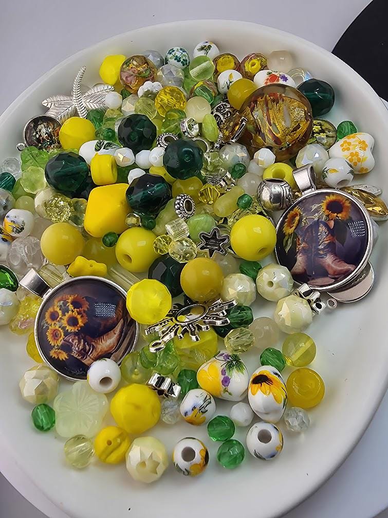 A white plate filled with a variety of colorful beads, charms, and other decorative items.