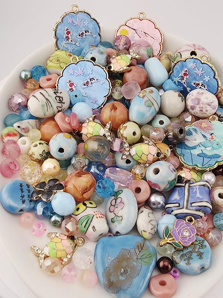 The image is a collection of various colorful beads, charms, and pendants arranged on a white surface.
