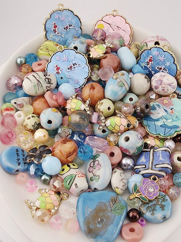 The image is a collection of various colorful beads, charms, and pendants arranged on a white surface.