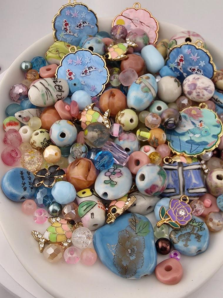 The image is a collection of various colorful beads, charms, and trinkets arranged on a white surface, such as a plate or a table.