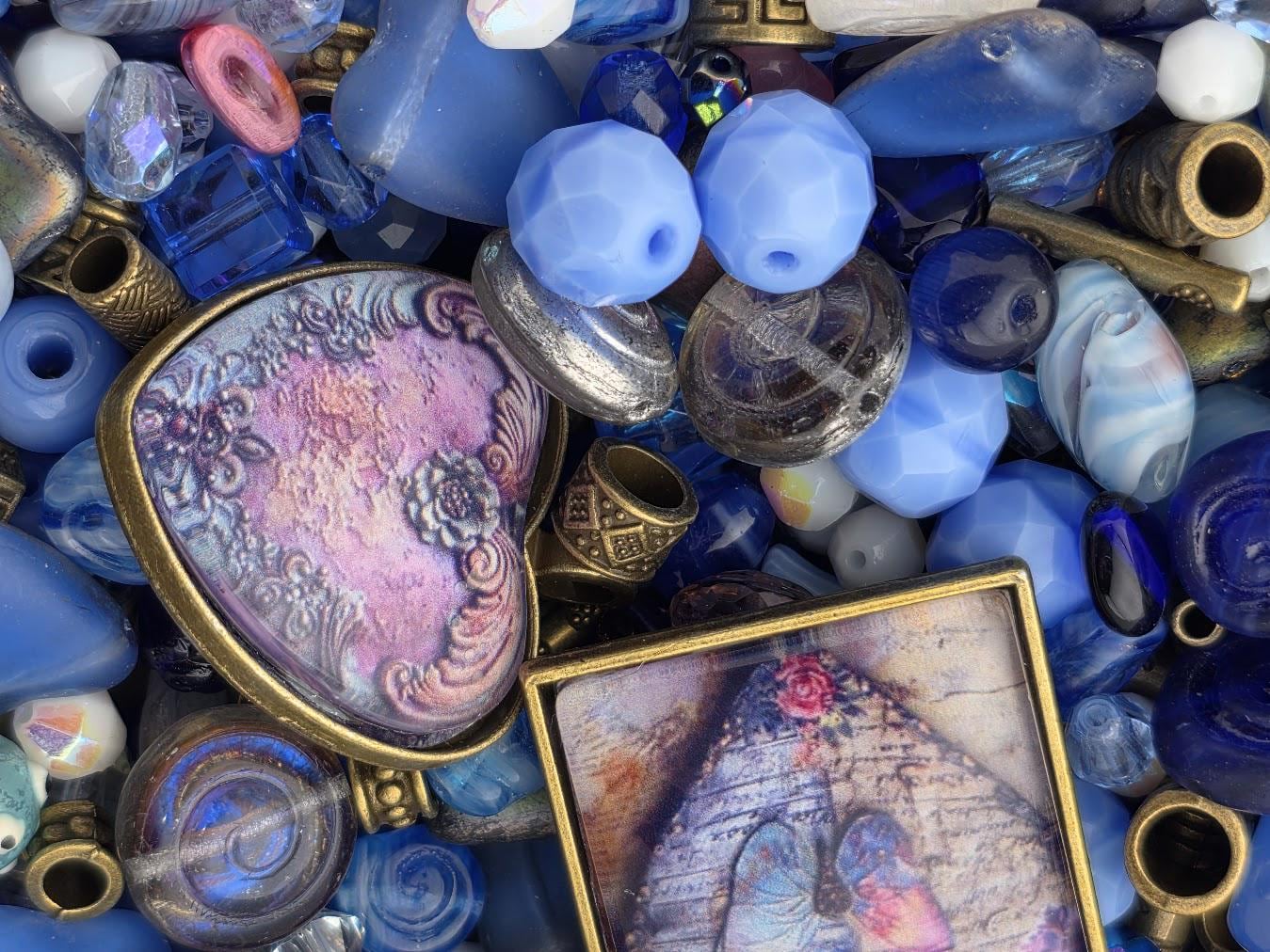 a variety of colorful beads, including blue, purple, and gold, as well as some metal objects. There is also a framed image of a butterfly among the beads.