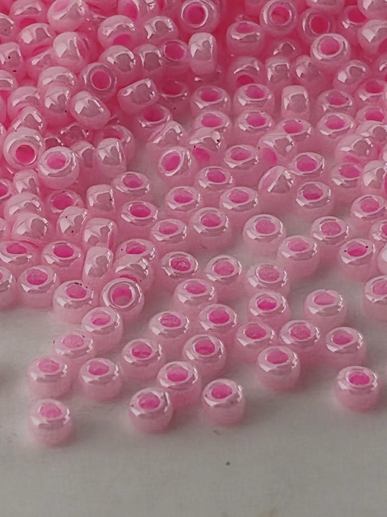 a close-up view of numerous small, round, and shiny pink beads scattered across a surface.