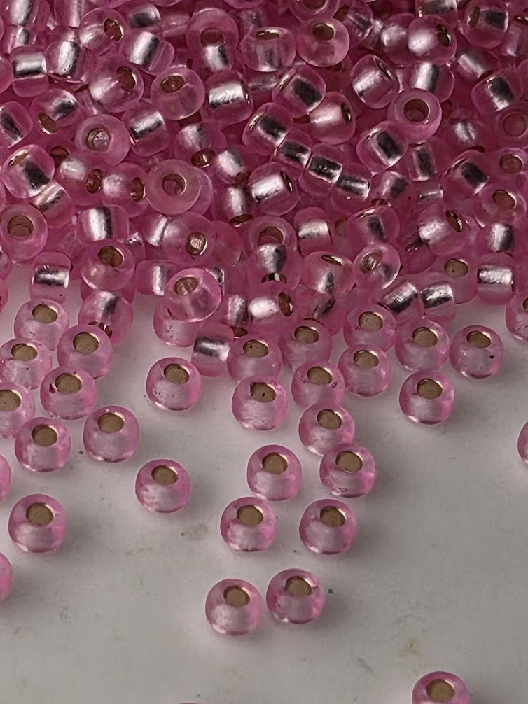 a collection of pink glass beads scattered across a surface, with some of the beads overlapping each other.