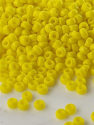 a large pile of bright yellow plastic beads scattered on a white surface.