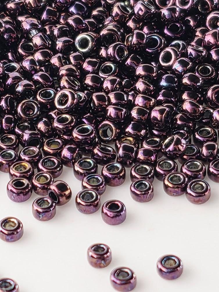 a large pile of small, shiny purple beads scattered across a white background.
