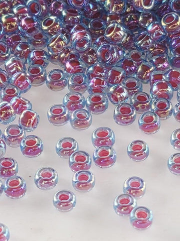 a collection of small, clear beads in various colors, including shades of blue, pink, and purple, scattered across a white surface.