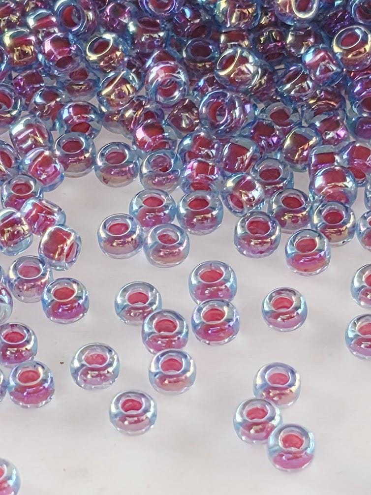 a collection of small, clear beads in various colors, including shades of blue, pink, and purple, scattered across a white surface.