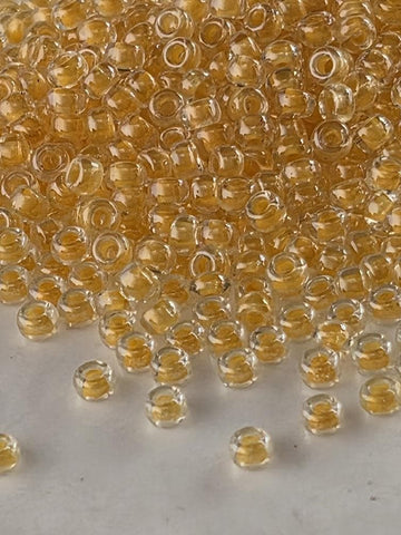 a large pile of clear, small, yellow beads scattered across a white surface.