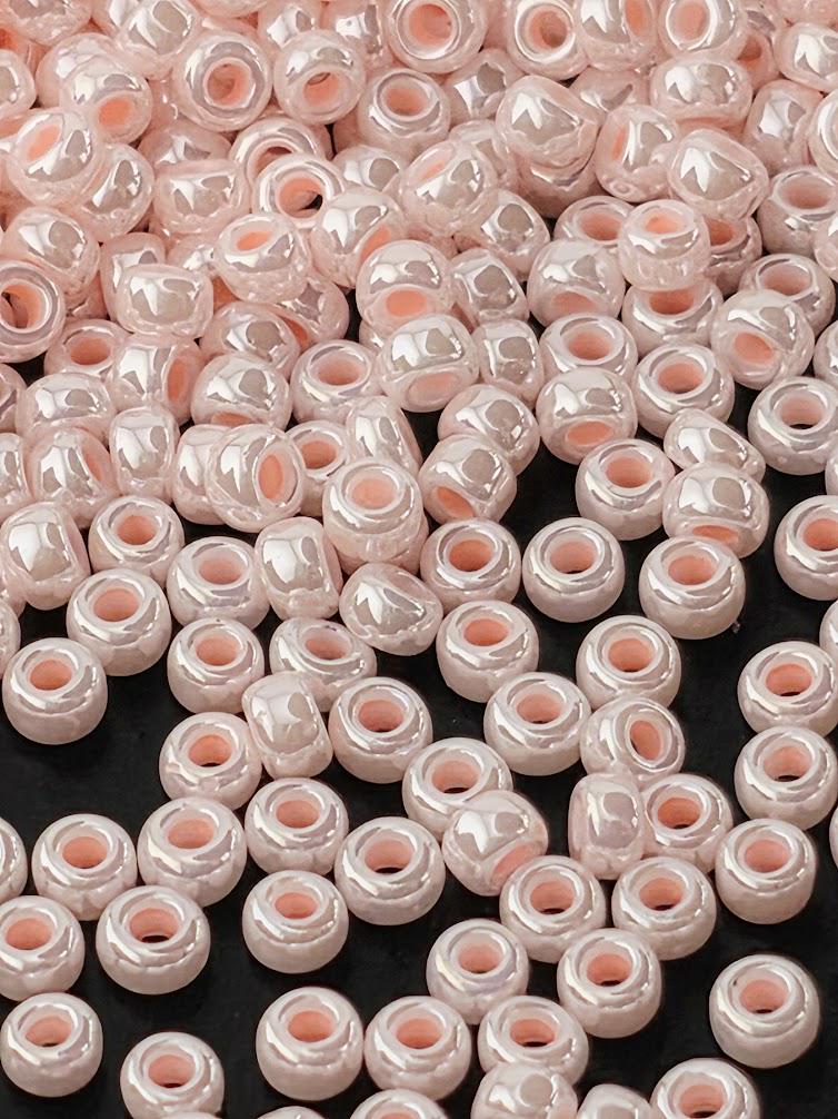 a large number of small, round beads in shades of pink and white, scattered across a dark background.