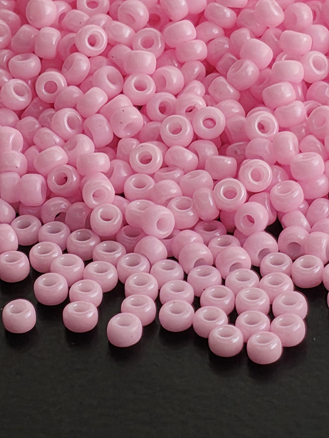 a large pile of small, round, pink beads scattered on a surface.