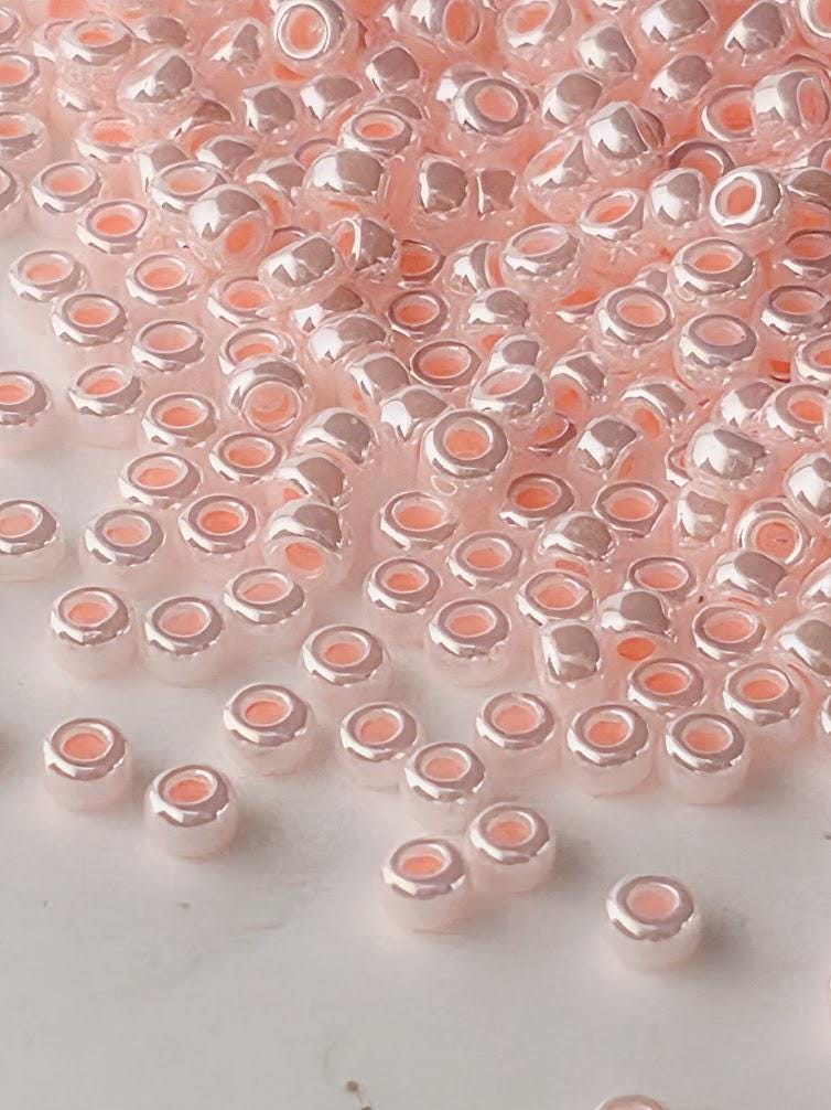 a close-up view of numerous small, round beads in shades of pink and white, scattered across a surface.