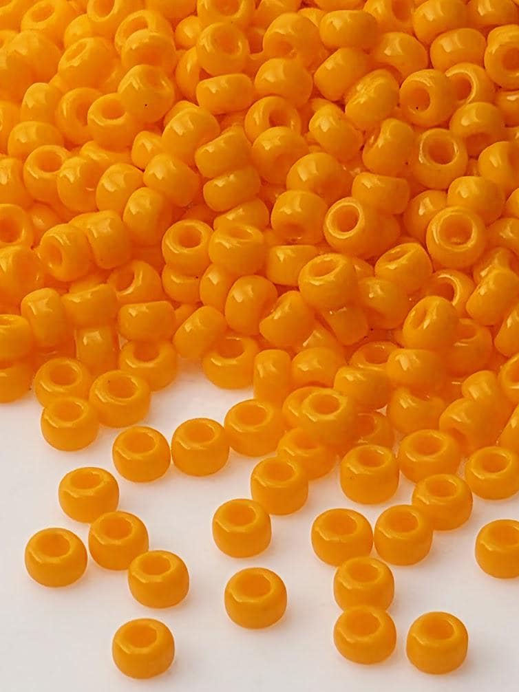 a large pile of bright orange beads scattered across a white surface.