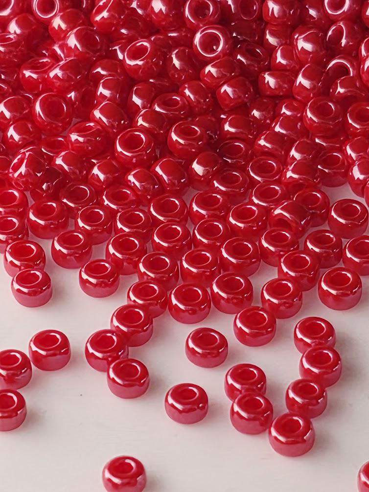 a large pile of red, shiny beads scattered across a white surface.