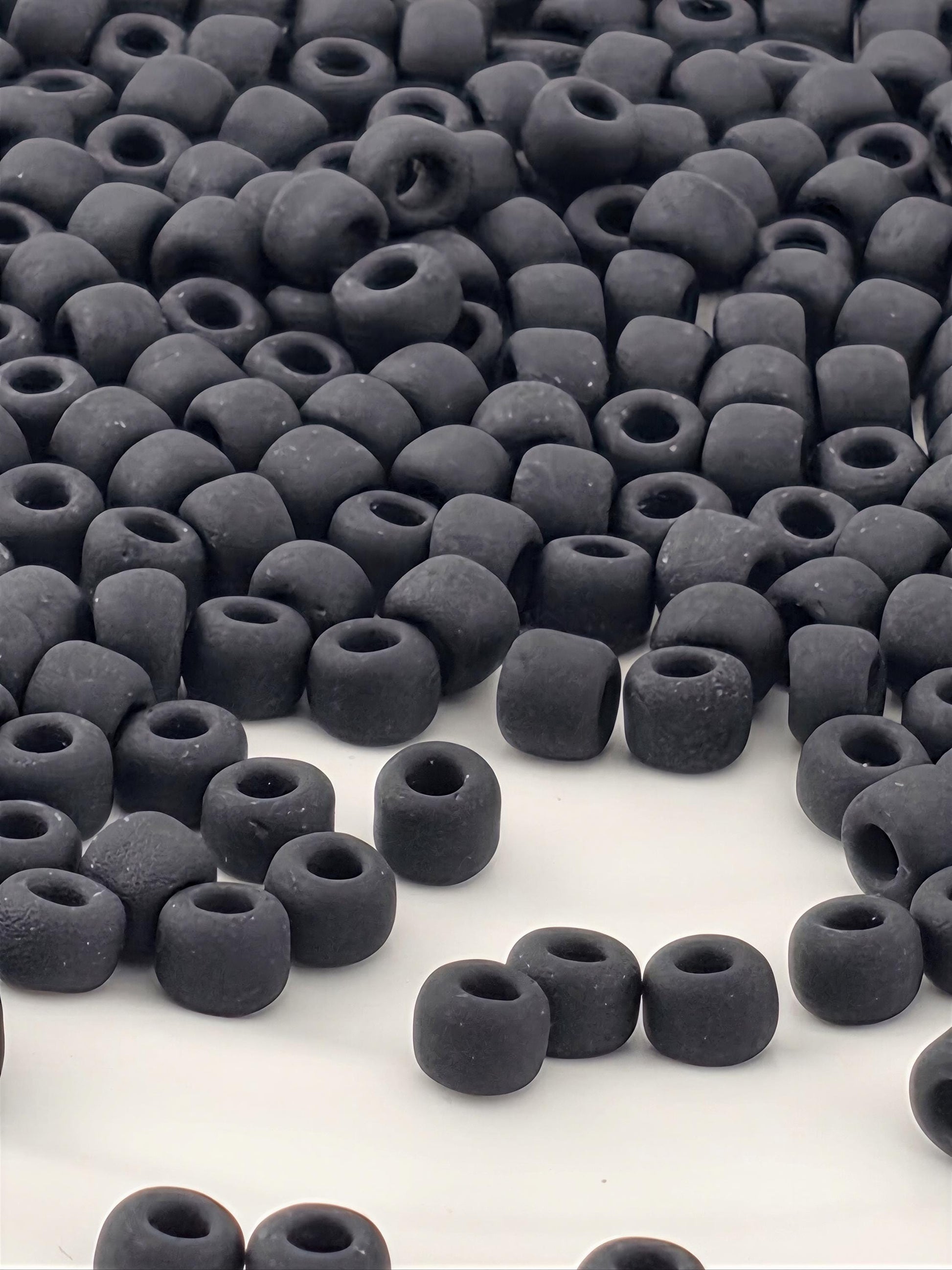 a large pile of black beads or objects scattered across a white background.