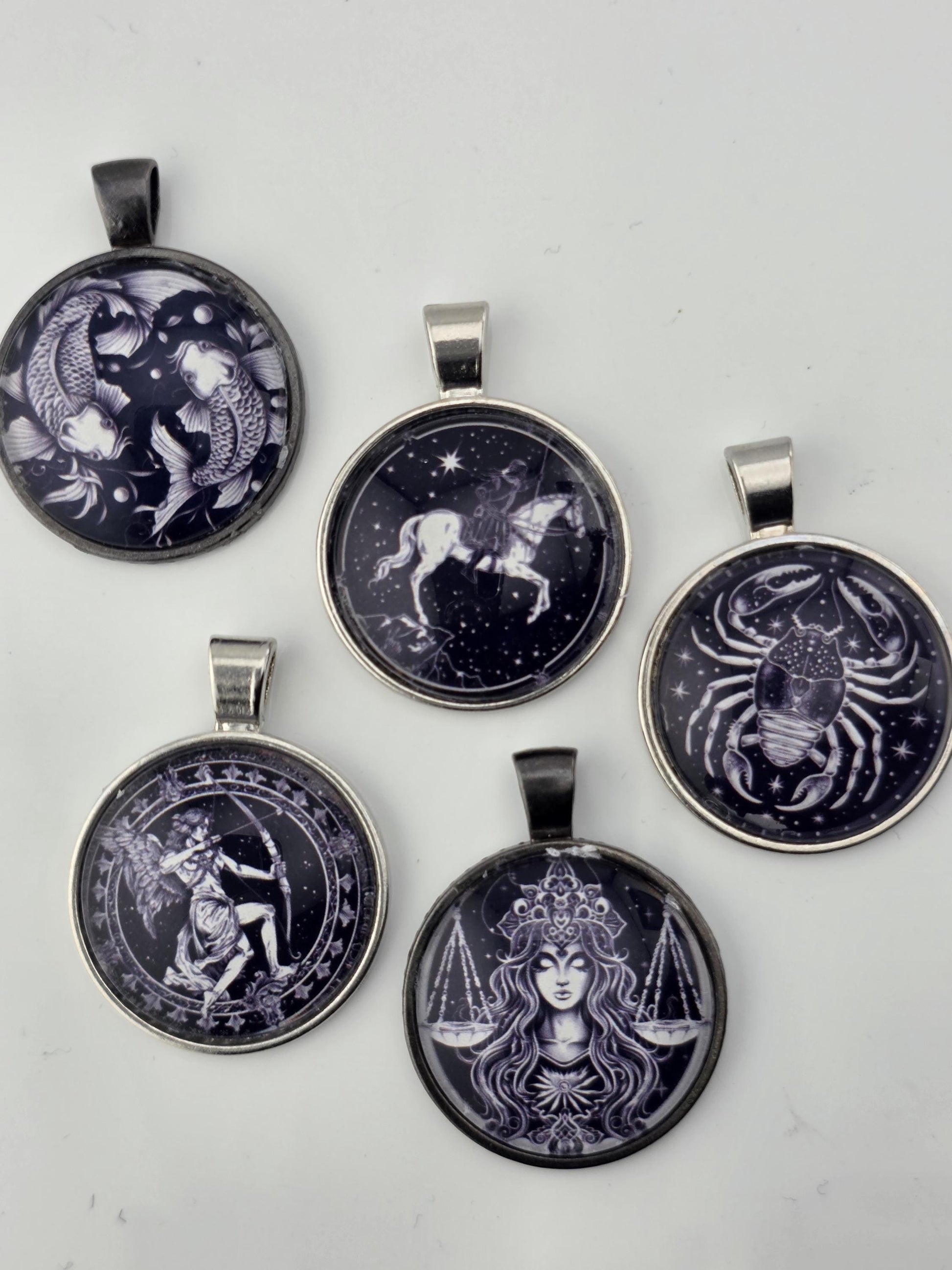 five round pendants with various designs, including astrological symbols and celestial imagery.