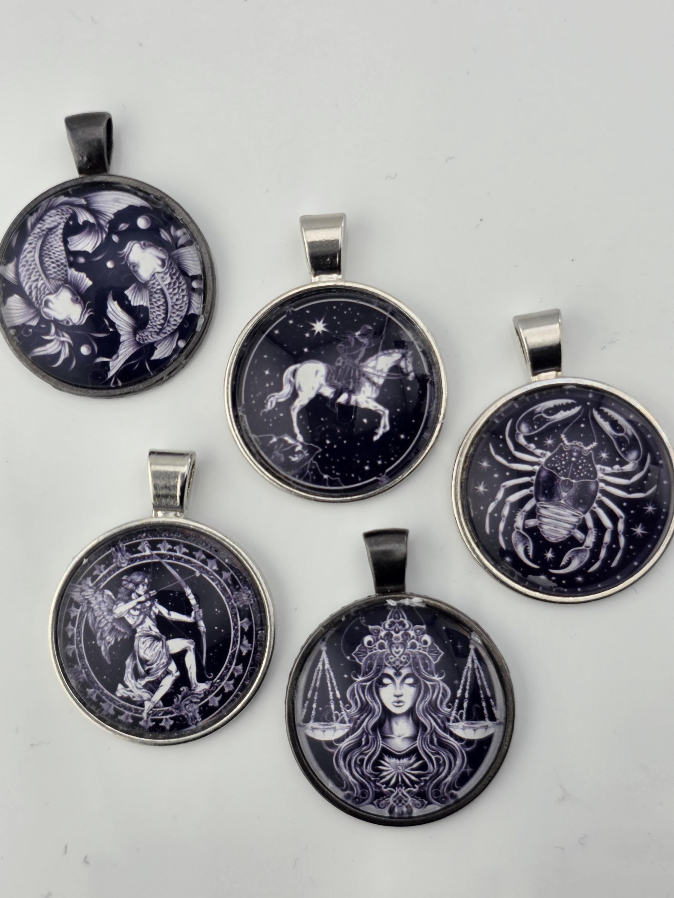 five round pendants with various designs, including astrological symbols and celestial imagery.