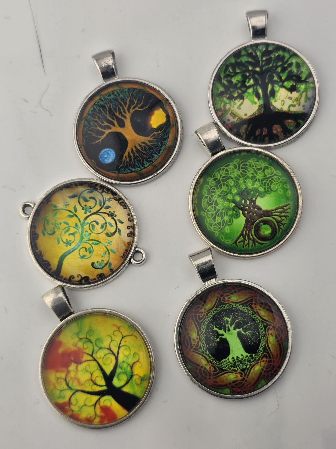 A collection of various beads, charms, and pendants in shades of green, gold, and other colors, arranged in a visually appealing manner.