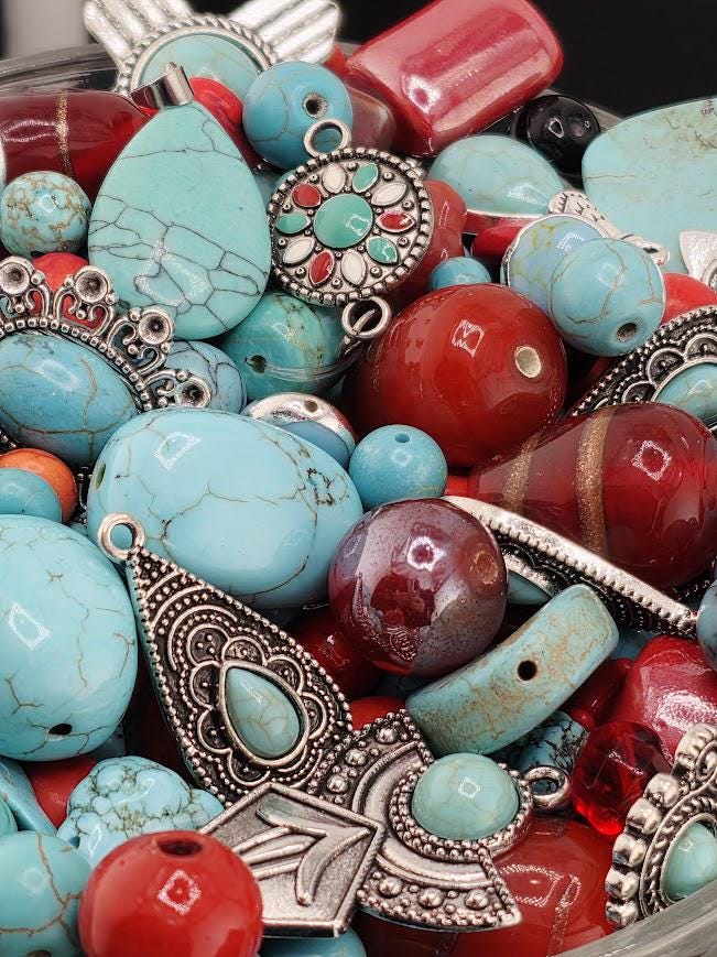 The image is a close-up of a collection of various colorful beads, charms, and ornaments, including turquoise, red, and silver elements.