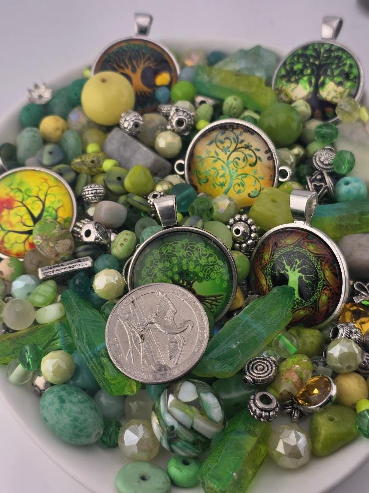 a collection of various colorful beads, charms, and pendants, including a silver coin, arranged on a white surface.