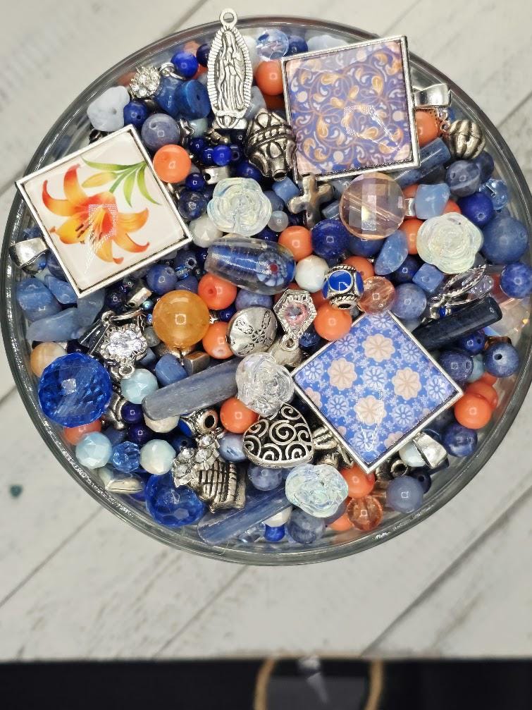 A glass bowl filled with various colorful beads, charms, and other decorative items.