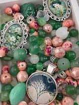 a variety of colorful beads, charms, and pendants, including green, pink, and white beads, as well as some with floral designs.