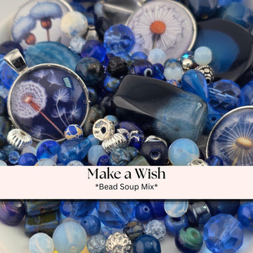A collection of various beads, charms, and pendants in shades of blue, silver, and black, arranged in a visually appealing manner.
