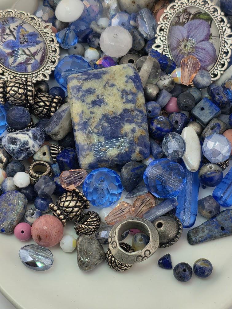 The image is a collection of various beads, charms, and other decorative items, including glass beads, metal beads, and gemstones, arranged on a surface.