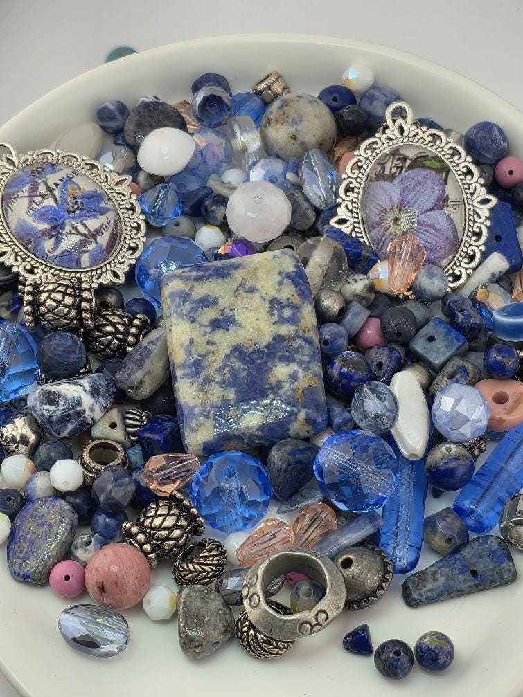 a variety of colorful beads, gemstones, and metal pieces arranged on a white surface, creating a visually appealing and diverse collection.